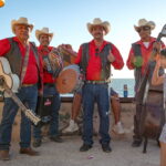 Group of musicians in cowboy hats and red shirts