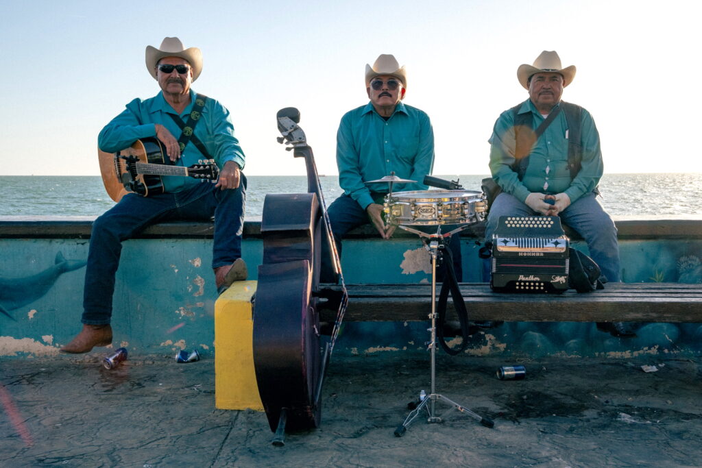 Three musicians in blue shirts and cowboy hats