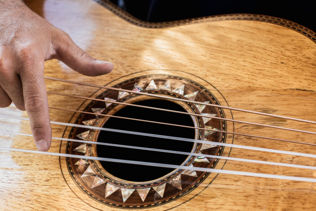 Detail of fingers plucking at a guitarrón strings