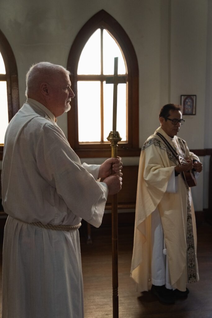 deacon with cross, priest with ukelele