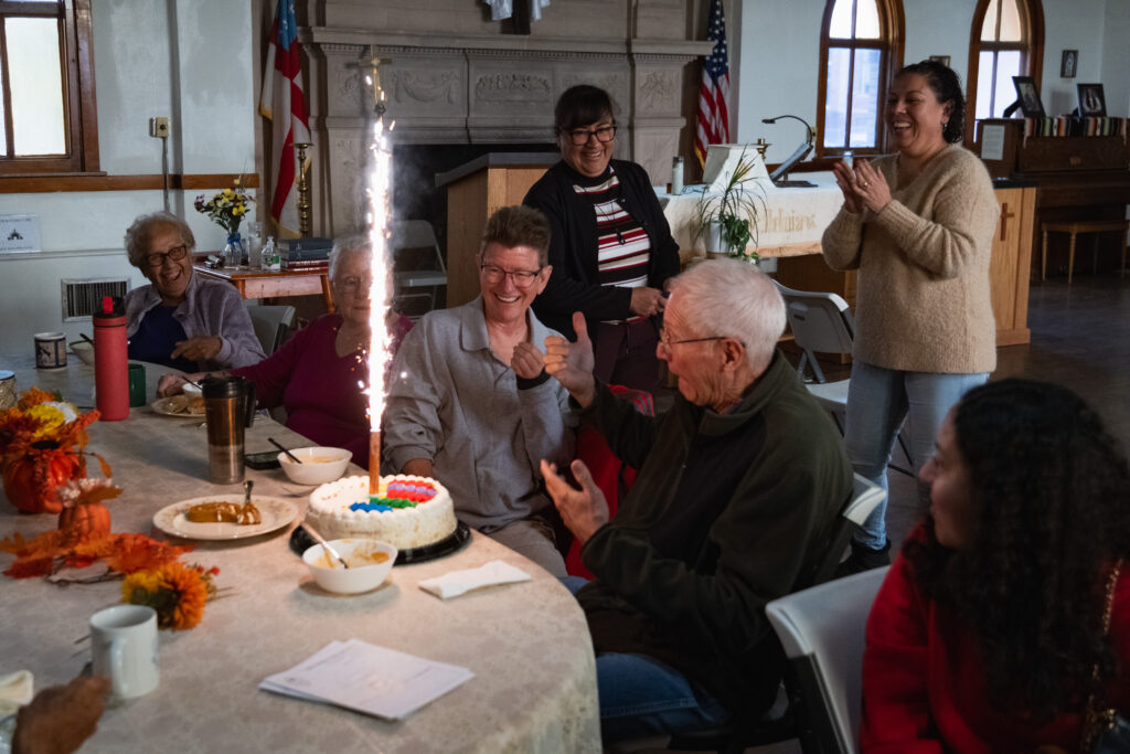 people seated at a table with a birthday cake and roman candle