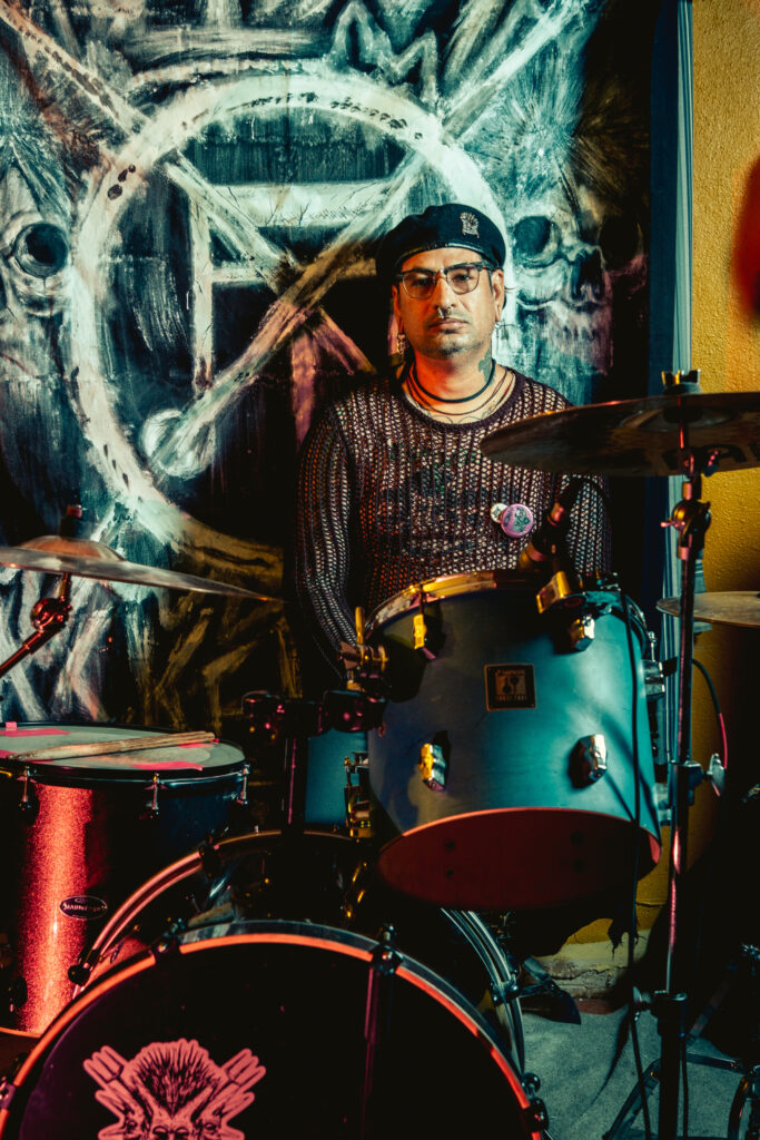 Man in beret sits at drum kit