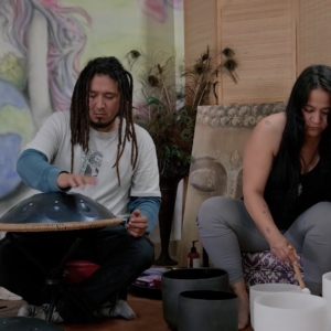 man and woman playing metal and singing bowls