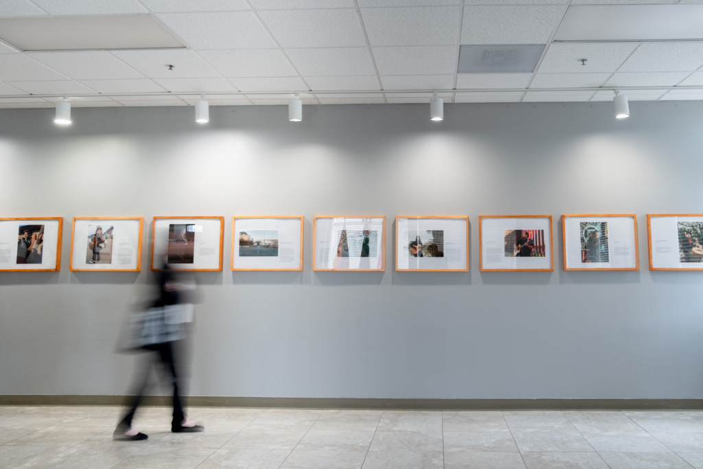 Blurred gallery visitor with framed photos in background